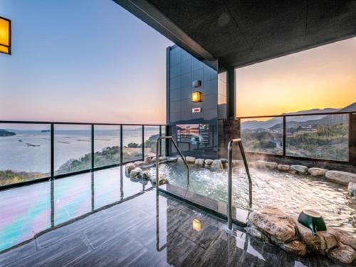 a glass house with a plunge pool and a view of the ocean at LiVEMAX RESORT Aki Miyahama Onsen in Hatsukaichi