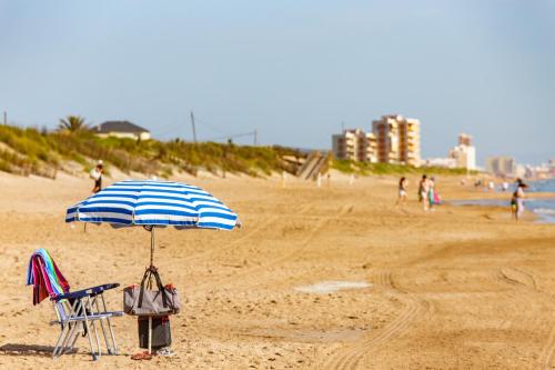 a beach with a chair and an umbrella on the sand at Cullera Panoramic Sea Views Apartment in Cullera