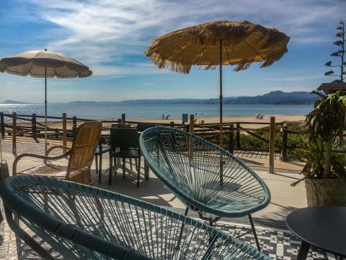 a patio with chairs and umbrellas on the beach at Cullera Panoramic Sea Views Apartment in Cullera