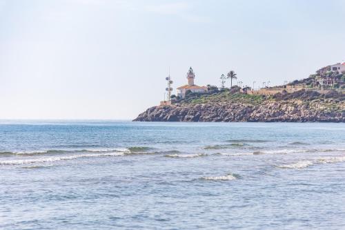 a body of water with a lighthouse on an island at Cullera Panoramic Sea Views Apartment in Cullera