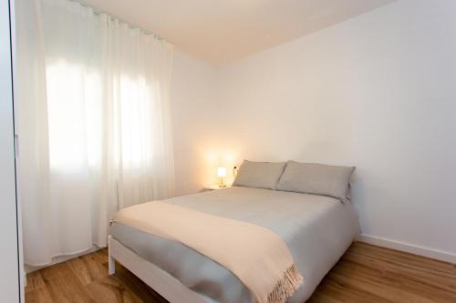 a white bedroom with a bed with a light on it at Cullera Panoramic Sea Views Apartment in Cullera
