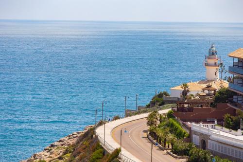a lighthouse on a hill next to the ocean at Cullera Panoramic Sea Views Apartment in Cullera