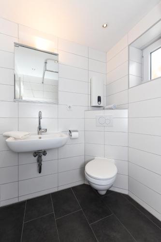 a white bathroom with a toilet and a sink at Haus Nordseepferdchen in Bensersiel