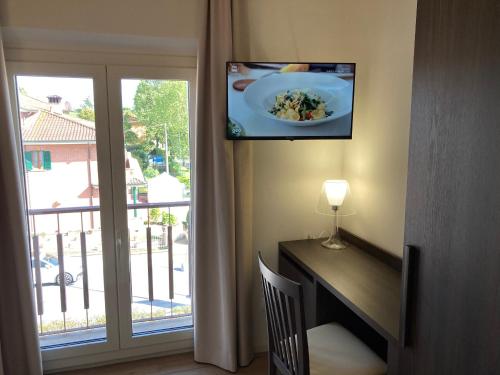 a room with a desk with a plate of food and a window at Hotel Belvedere in Galleno
