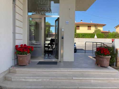 a hotel entrance with two pots of red flowers at Hotel Belvedere in Galleno