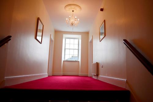 an empty hallway with a red carpet and a window at Ashbrook Arms Townhouse and Restaurant in Durrow