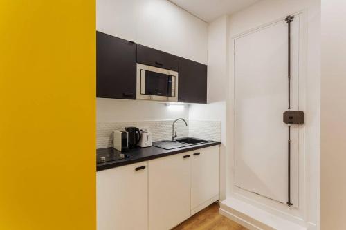 une cuisine avec des armoires blanches et un micro-ondes dans l'établissement Chic Saint-Germain-des-Prés Studio for 4 - Prime location, à Paris