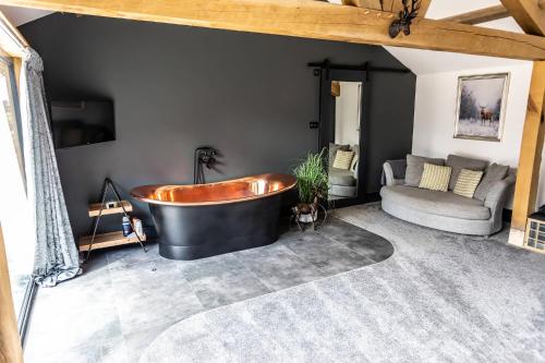 a large bathroom with a tub and a couch at Wood View Barn in Iron Acton