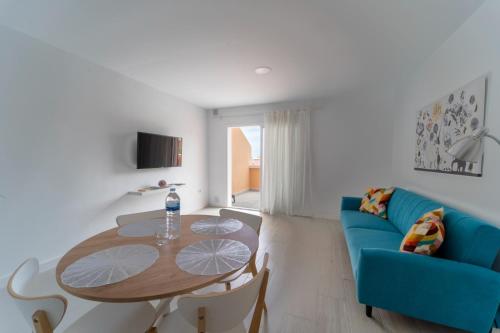 a living room with a table and a blue couch at Comfortable Apartment Los Cristianos. Free Wifi. in Arona