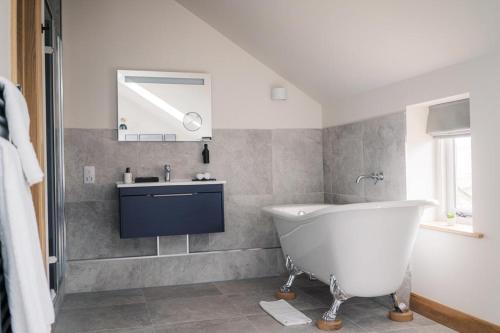 a bathroom with a white tub and a sink at The Blind Bull in Little Hucklow
