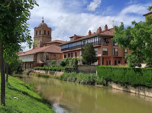 a river in front of a building with a church at Apto. Completo, La Ribera in Aguilar de Campóo