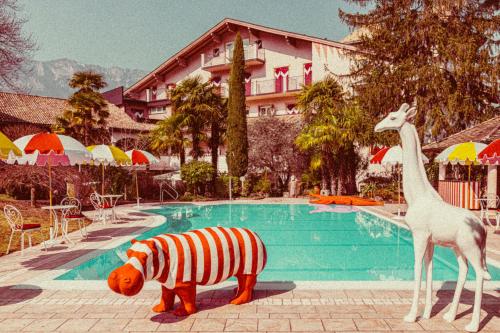 Un faux zèbre et une girafe à côté d'une piscine dans l'établissement Amadeus Ora & Amore, à Caldaro