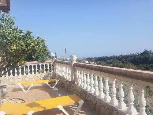 un balcón con 2 sillas y un banco amarillo en Villa Capricho Nerja, en Málaga