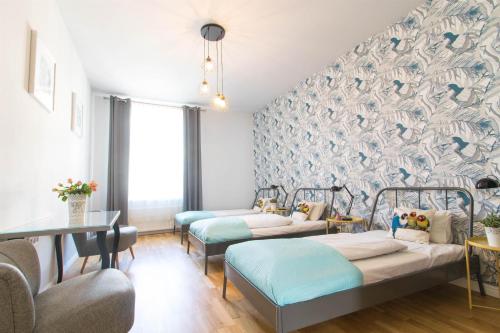 a room with three beds and a wall with bird wallpaper at Krupnicza Modern Old Town Apartments - by Upstairs in Kraków