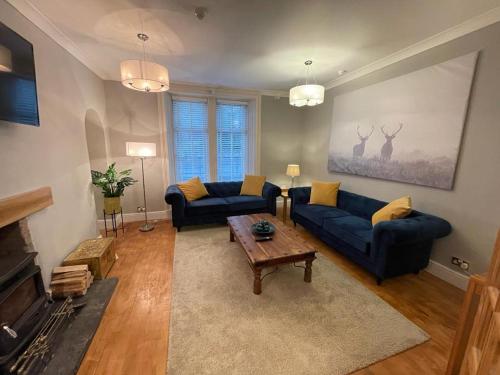 a living room with two blue couches and a coffee table at Elmbank Stay - Drymen in Drymen