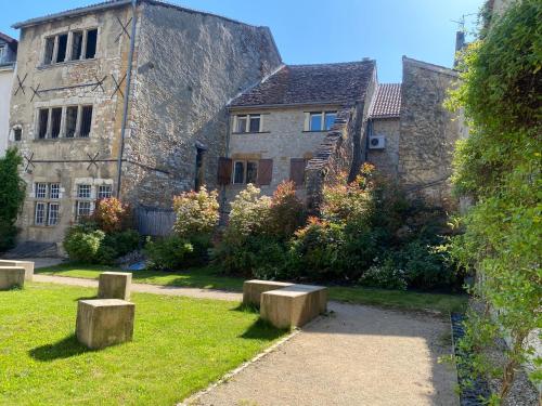an old stone building with stone benches in the yard at Logis Hôtel Vuillot in Cuiseaux