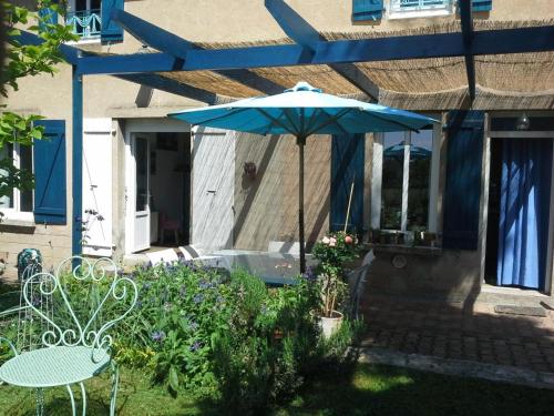 a patio with a table and a blue umbrella at Maison de campagne idéale pour familles, cavaliers, animaux acceptés, avec jardin clos et tout équipé. - FR-1-489-172 in Barrais-Bussolles