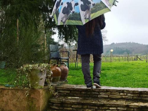 a woman is holding an umbrella in the rain at Maison de campagne idéale pour familles, cavaliers, animaux acceptés, avec jardin clos et tout équipé. - FR-1-489-172 in Barrais-Bussolles