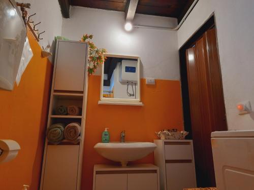 ein orangefarbenes Badezimmer mit einem Waschbecken und einem Spiegel in der Unterkunft Sweet House in Villamassargia