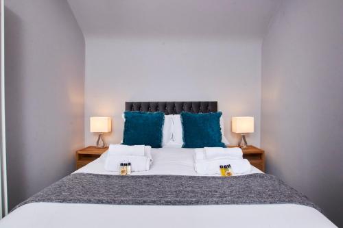 a bedroom with a large bed with blue pillows at Delven House, Apartment 6 in Castle Donington