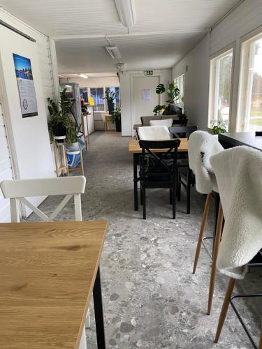 Cette chambre comprend des tables, des chaises blanches et des fenêtres. dans l'établissement Santtioranta Camping, à Uusikaupunki