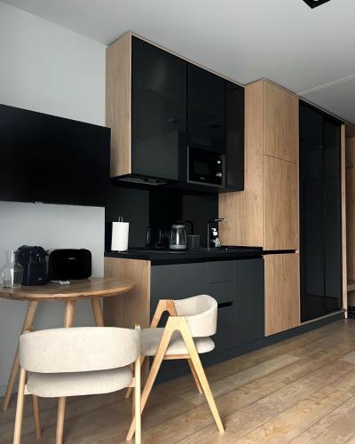 a kitchen with black cabinets and a table and chairs at SAVOIE Apartments Bukovel in Bukovel