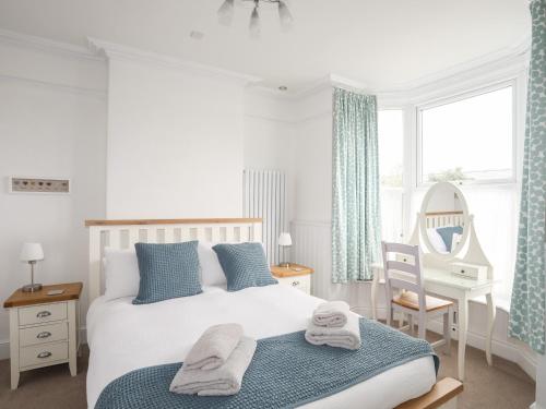 a bedroom with a bed and a chair and a mirror at Gwynle - Criccieth in Criccieth