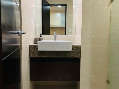 a bathroom with a white sink and a mirror at Josh's Place at One Eastwood Avenue Tower 1 in Manila