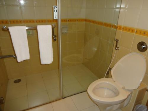 a bathroom with a toilet and a shower with towels at JP Chennai Hotel in Chennai