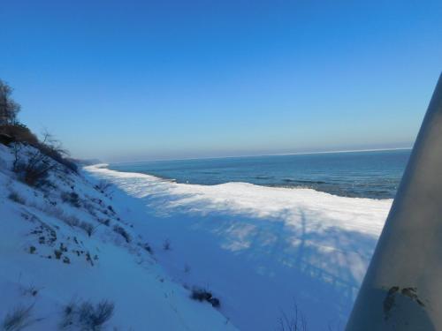 a view of a snow covered path next to the ocean at moderne 3-Raum Ferienwohnung Strandmöwe mit Panoramafenster in Ueckeritz