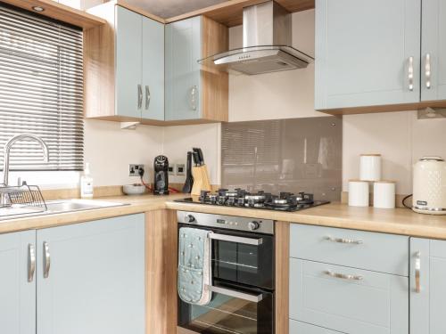 a kitchen with white cabinets and a stove top oven at Serena Lodge in Jedburgh