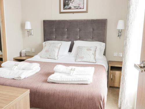 a bedroom with a large bed with two towels on it at Serena Lodge in Jedburgh