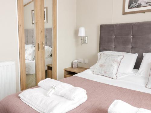 a bedroom with a large bed with a mirror at Serena Lodge in Jedburgh