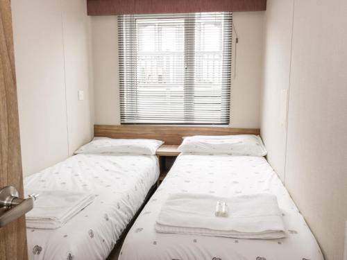 two beds in a room with a window at Serena Lodge in Jedburgh