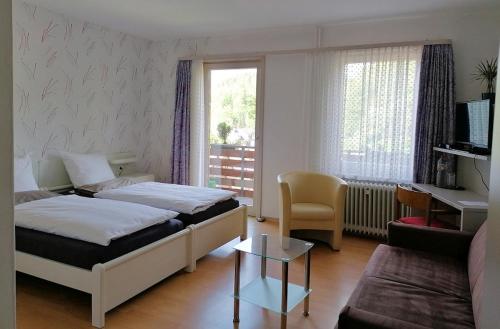 a hotel room with two beds and a living room at Hotel-Pension Waldhaus in Bad Grund