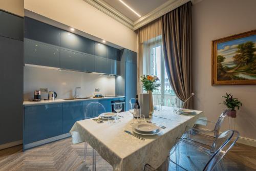 uma sala de jantar com uma mesa e armários azuis em Plaza View Luxury Apartment, Alba em Alba