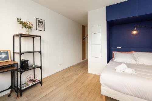 a bedroom with a large bed with a blue headboard at DIFY Eugene - Part Dieu in Lyon