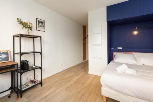 une chambre avec un grand lit avec une tête de lit bleue dans l'établissement DIFY Eugene - Part Dieu, à Lyon