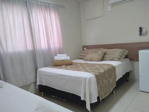 a bedroom with two beds and a window at Pousada Solar de Lourdes in Guarapari