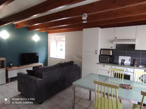 uma cozinha e uma sala de estar com uma mesa e um sofá em Le gîte de ty stumo1 em Neulliac