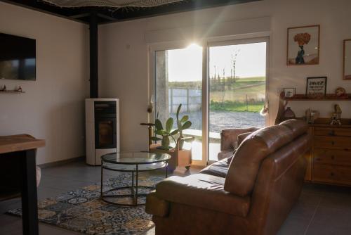 sala de estar con sofá y mesa de cristal en La Grange Du Bosquet, en Honnecourt-sur-lʼEscaut