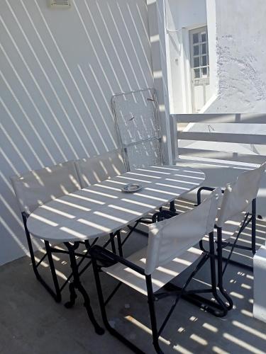 two white chairs and a picnic table on a porch at Chez Georges in Parikia