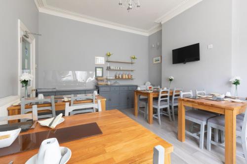 a dining room with tables and chairs and a tv at The Firs Bed and Breakfast in Plymouth