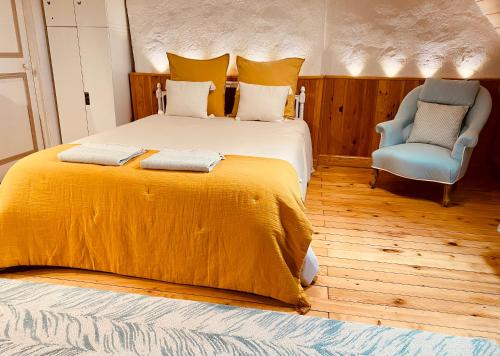 a bedroom with a large bed and a blue chair at La maison de Montaboulin in Châteauroux