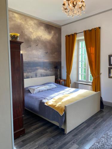 a bedroom with a bed with a painting on the wall at Le Chateau de Claids in Saint-Patrice-de-Claids