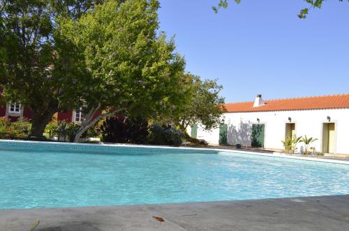 a swimming pool with trees and a building at Hortas de Baixo in Luz de Tavira