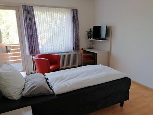 a bedroom with a bed and a chair and a window at Hotel-Pension Waldhaus in Bad Grund
