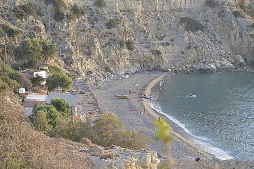 a beach with a bunch of people in the water at Tsaner Apartment and Rooms in Matala