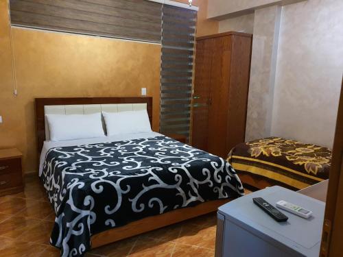 een slaapkamer met een bed met een zwart-witte deken bij Kompleksi GJONI in Fier