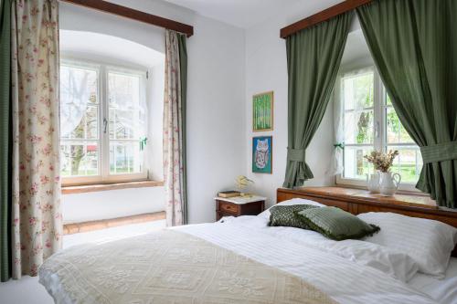 a bedroom with a white bed and two windows at House 1797 - Charm of Slovenian Vintage in Dob